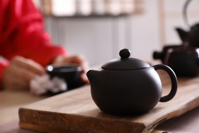 Photo of Traditional tea ceremony, focus on teapot. Guest enjoying beverage, closeup
