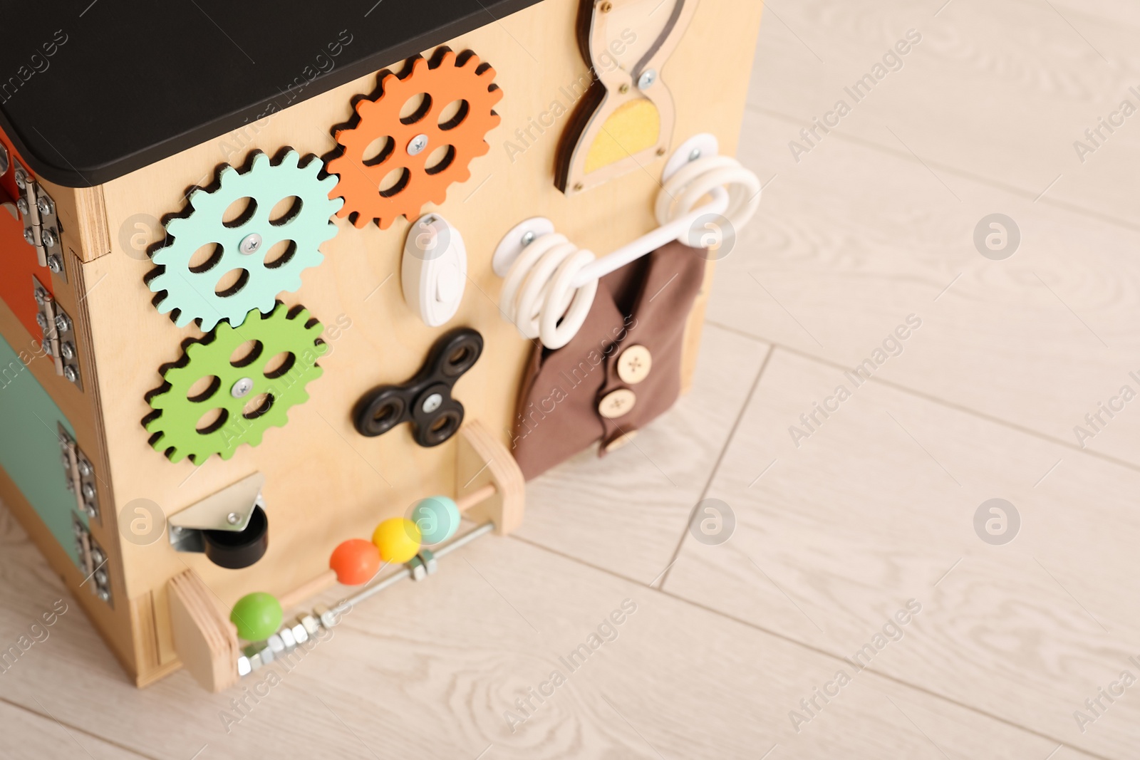 Photo of Busy board house on floor indoors, closeup view space for text. Baby sensory toy