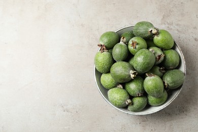 Fresh green feijoa fruits in bowl on light grey table, top view. Space for text