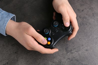 Photo of Man using wireless game controller at grey table, closeup