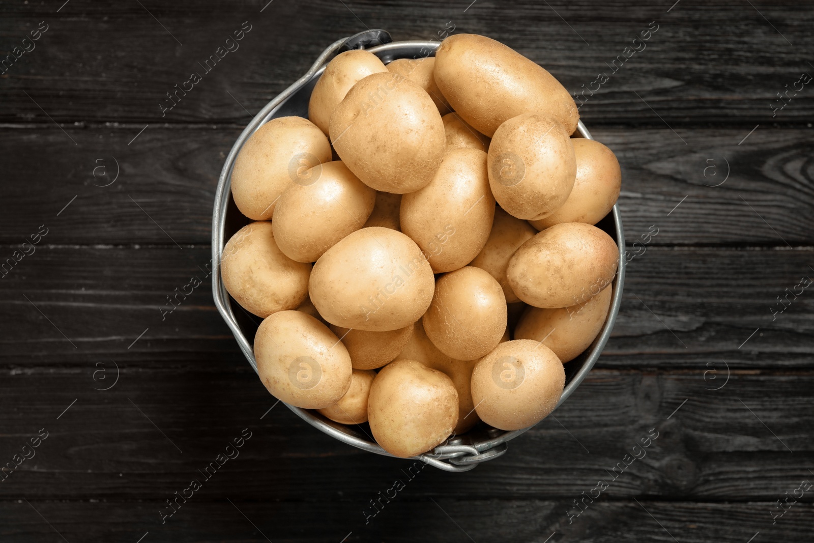 Photo of Raw fresh organic potatoes on black wooden background, top view