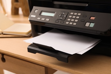 Closeup view of new modern printer with control panel on wooden table