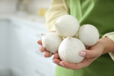 Photo of Woman holding white onions indoors, closeup view
