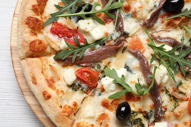 Tasty pizza with anchovies, arugula and olives on white table, top view