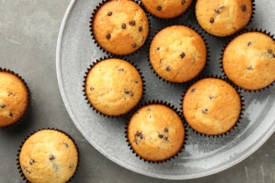 Delicious freshly baked muffins with chocolate chips on gray table, top view