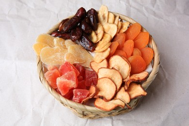 Photo of Wicker basket with different dried fruits on paper