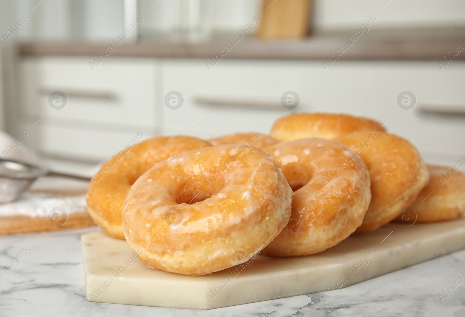 Photo of Delicious glazed donuts on marble table, closeup