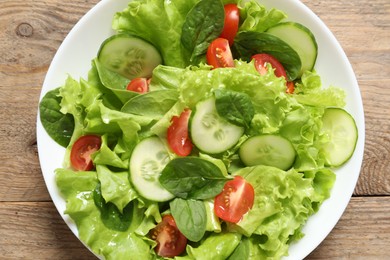 Delicious salad in bowl on wooden table, top view