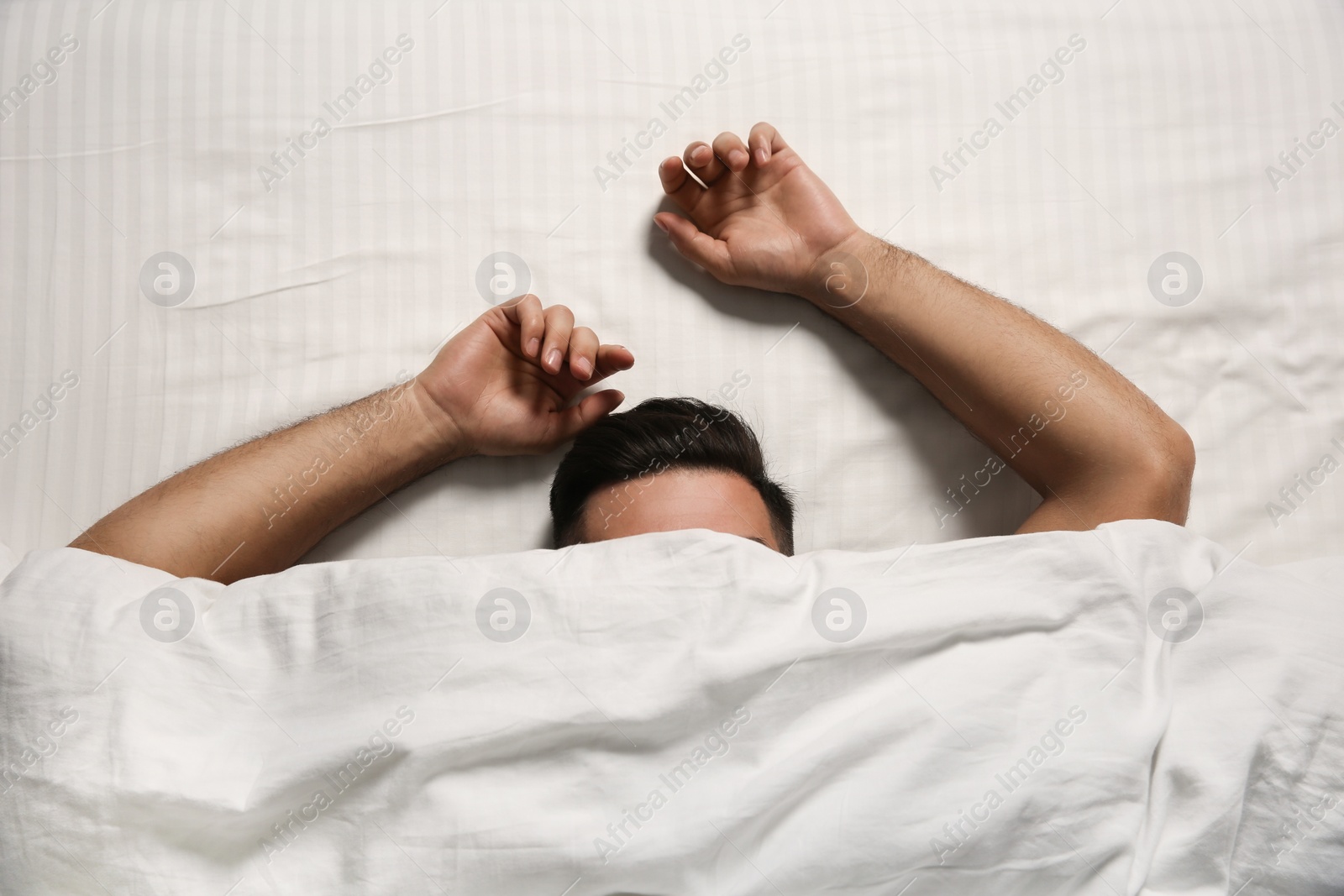 Photo of Man sleeping under soft blanket in bed at home, top view