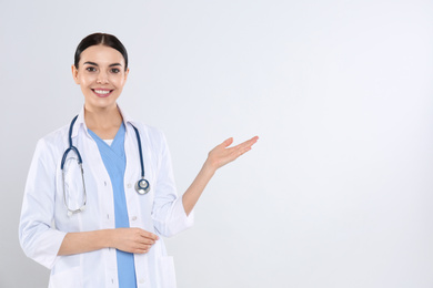 Portrait of young doctor with stethoscope on white background