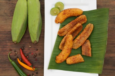 Delicious fried bananas, fresh fruits and different peppers on wooden table, flat lay