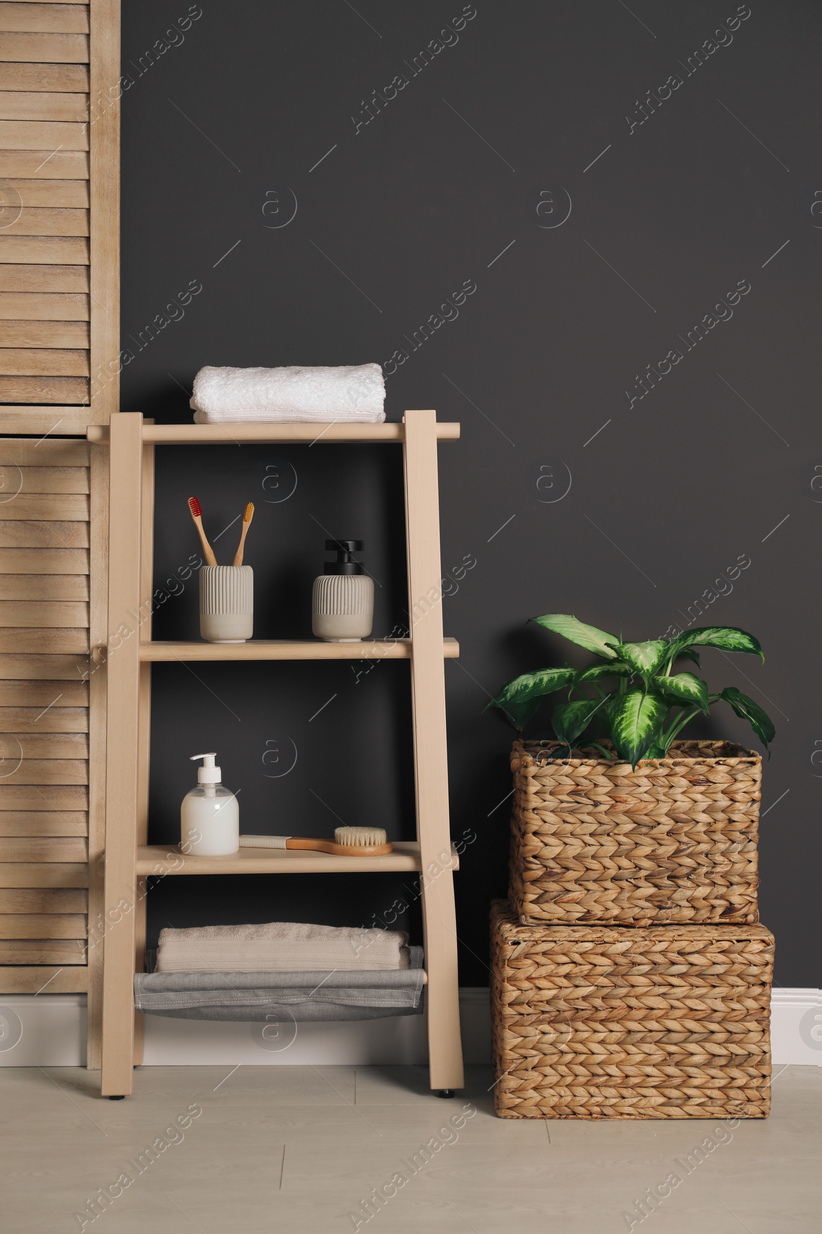 Photo of Wooden shelving unit with toiletries near black wall indoors. Bathroom interior element