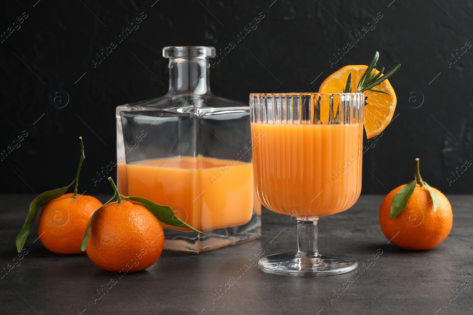 Photo of Delicious tangerine liqueur and fresh fruits on grey table