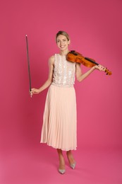 Beautiful woman with violin on pink background