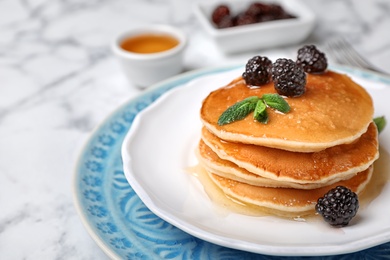 Tasty pancakes with honey and berries on table