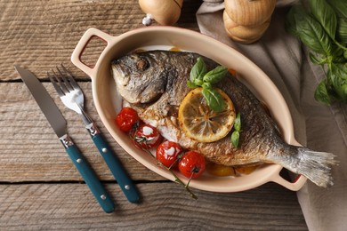 Delicious roasted dorado fish served on wooden table, flat lay