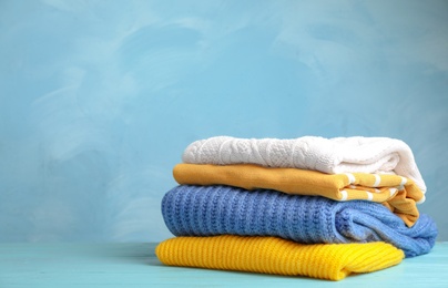 Photo of Stack of folded knitted sweaters on table. Space for text