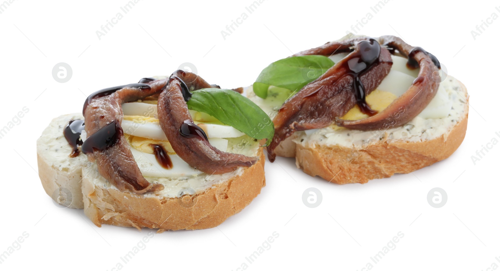 Photo of Delicious bruschettas with anchovies, eggs, basil and sauce on white background