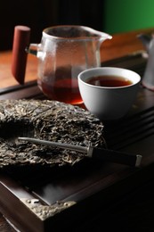 Disc shaped pu-erh tea and knife on wooden tray