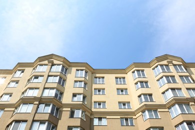 Photo of Exterior of multi storey apartment building against blue sky, low angle view
