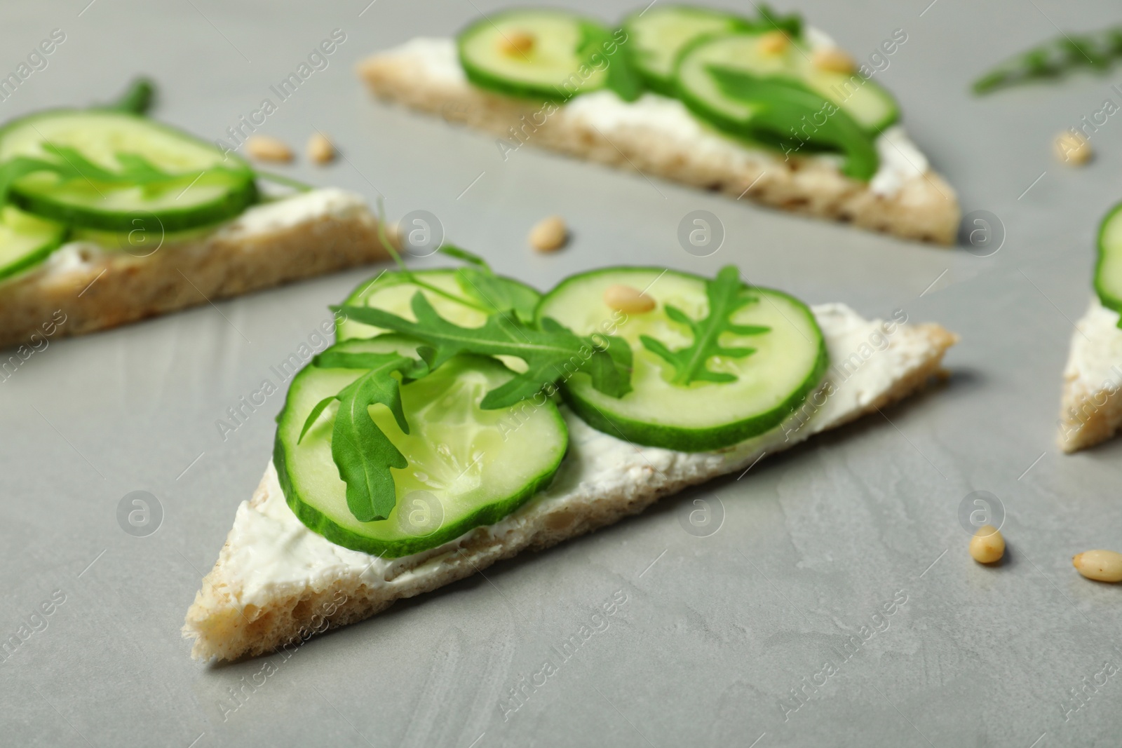 Photo of Traditional English cucumber sandwiches on grey table