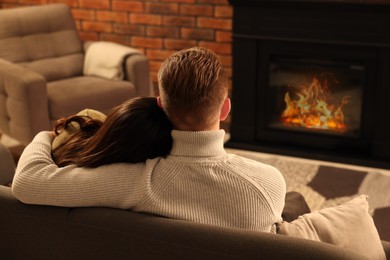 Lovely couple spending time together near fireplace at home, back view