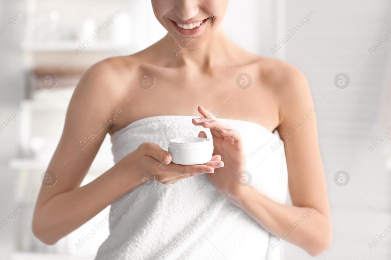 Photo of Young woman with jar of body cream at home