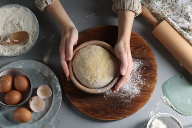 Photo of Woman making dough at grey table, top view