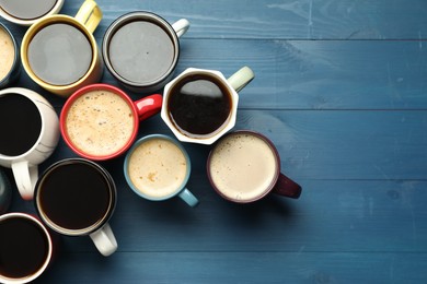 Many cups of different coffee drinks on blue wooden table, flat lay. Space for text