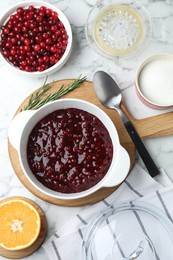 Photo of Fresh cranberry sauce in bowl served on white marble table, flat lay