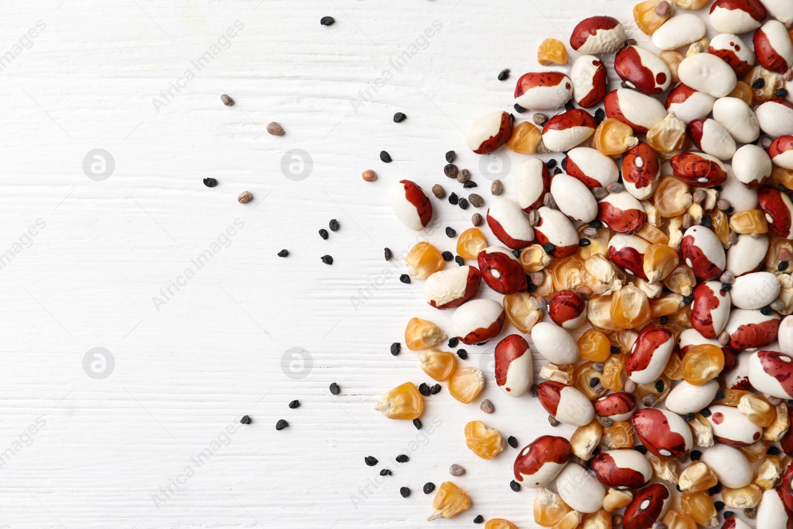 Photo of Mixed vegetable seeds on white wooden background, flat lay