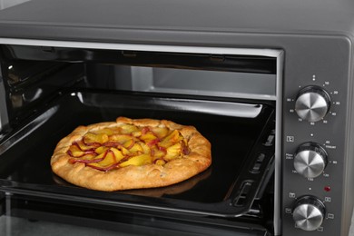 Photo of Open electric oven with delicious pie, closeup
