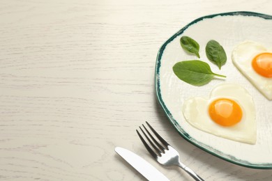 Photo of Heart shaped fried eggs served on white wooden table, space for text