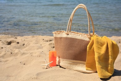 Photo of Sunscreen, starfish, bag and towel on beach, space for text. Sun protection care