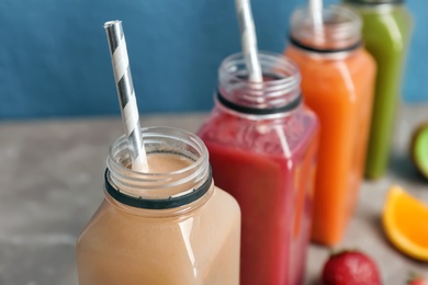 Photo of Bottles with healthy detox smoothies on table, closeup