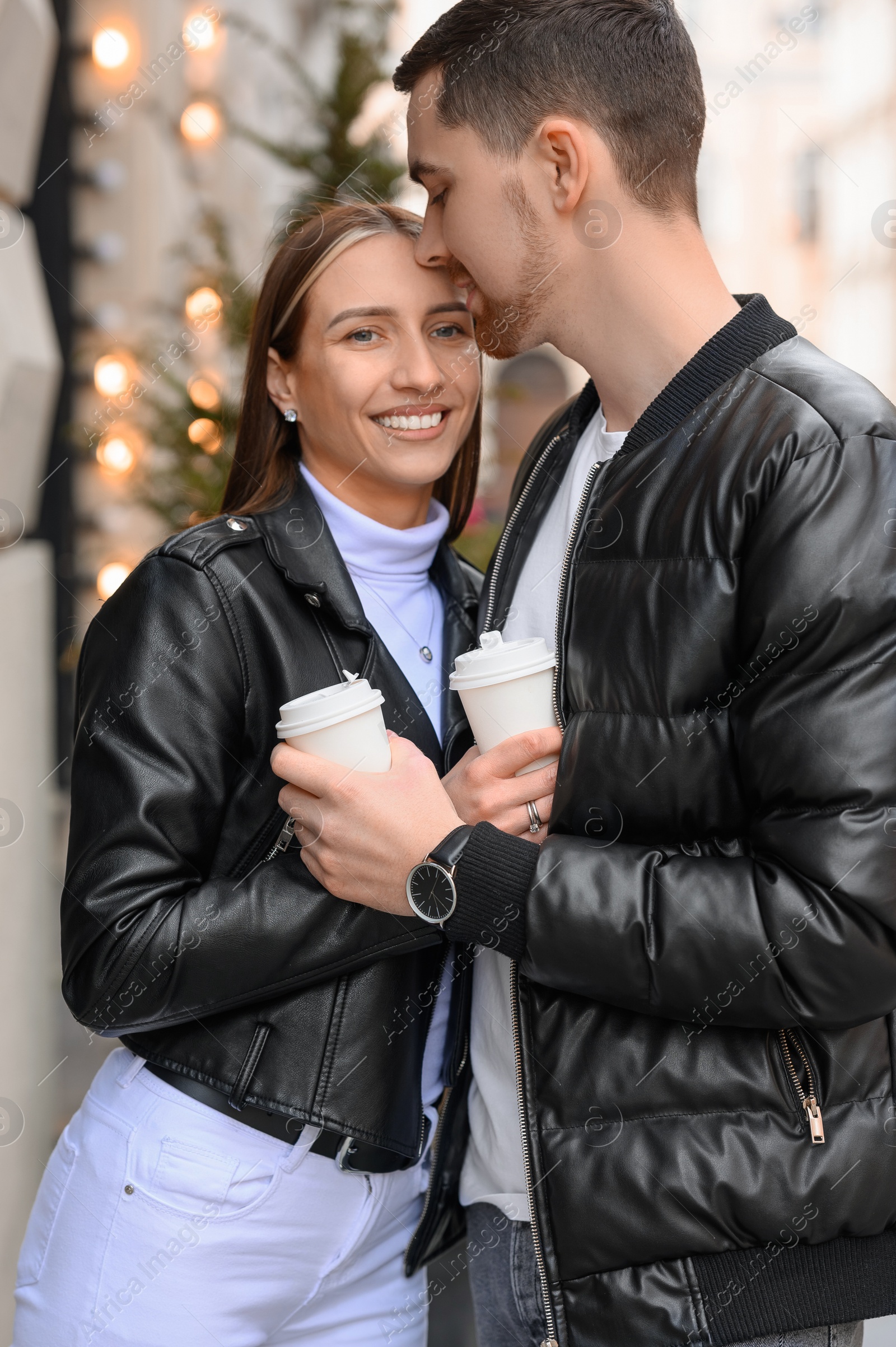 Photo of Lovely young couple with cups of coffee enjoying time together outdoors, closeup. Romantic date