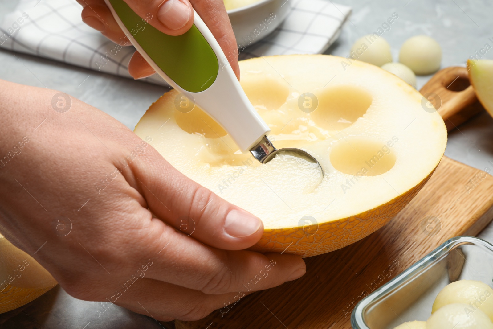 Photo of Woman making melon balls at table, closeup