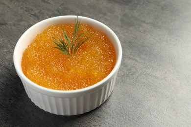Photo of Fresh pike caviar and dill in bowl on grey table, closeup. Space for text