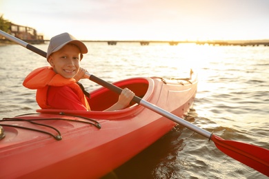 Photo of Happy boy kayaking on river. Summer camp activity