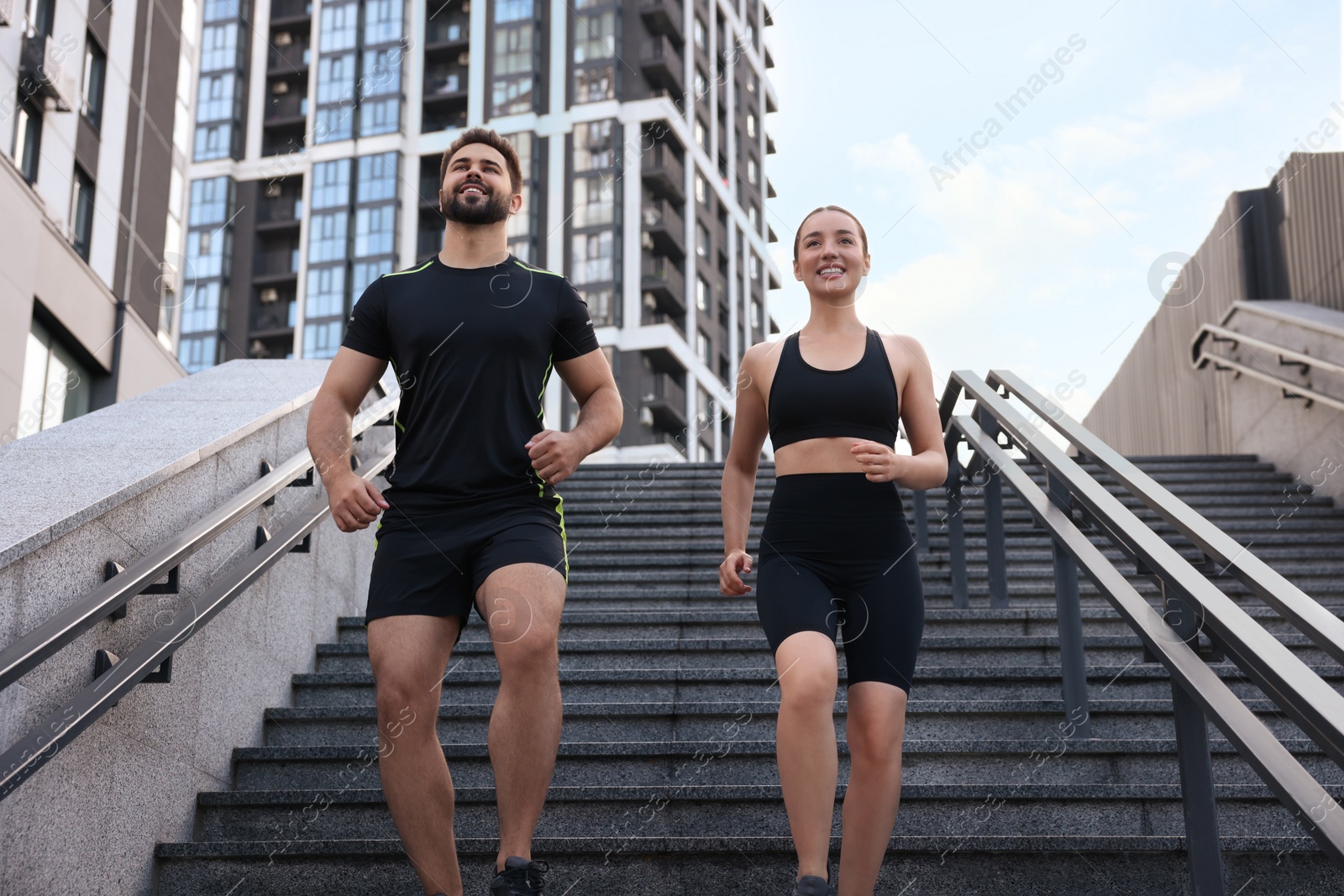 Photo of Healthy lifestyle. Happy couple running on steps outdoors, low angle view