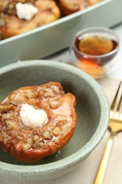 Tasty baked quince with nuts and cream cheese in bowl on table, closeup