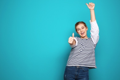 Photo of Happy young woman showing thumbs up on color background, space for text. Celebrating victory