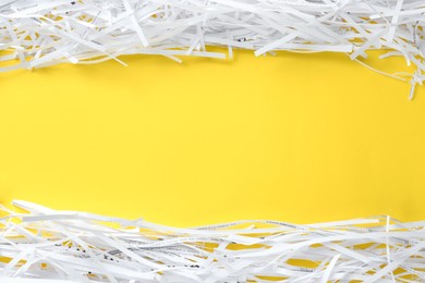 Photo of Shredded paper strips on yellow background, flat lay. Space for text