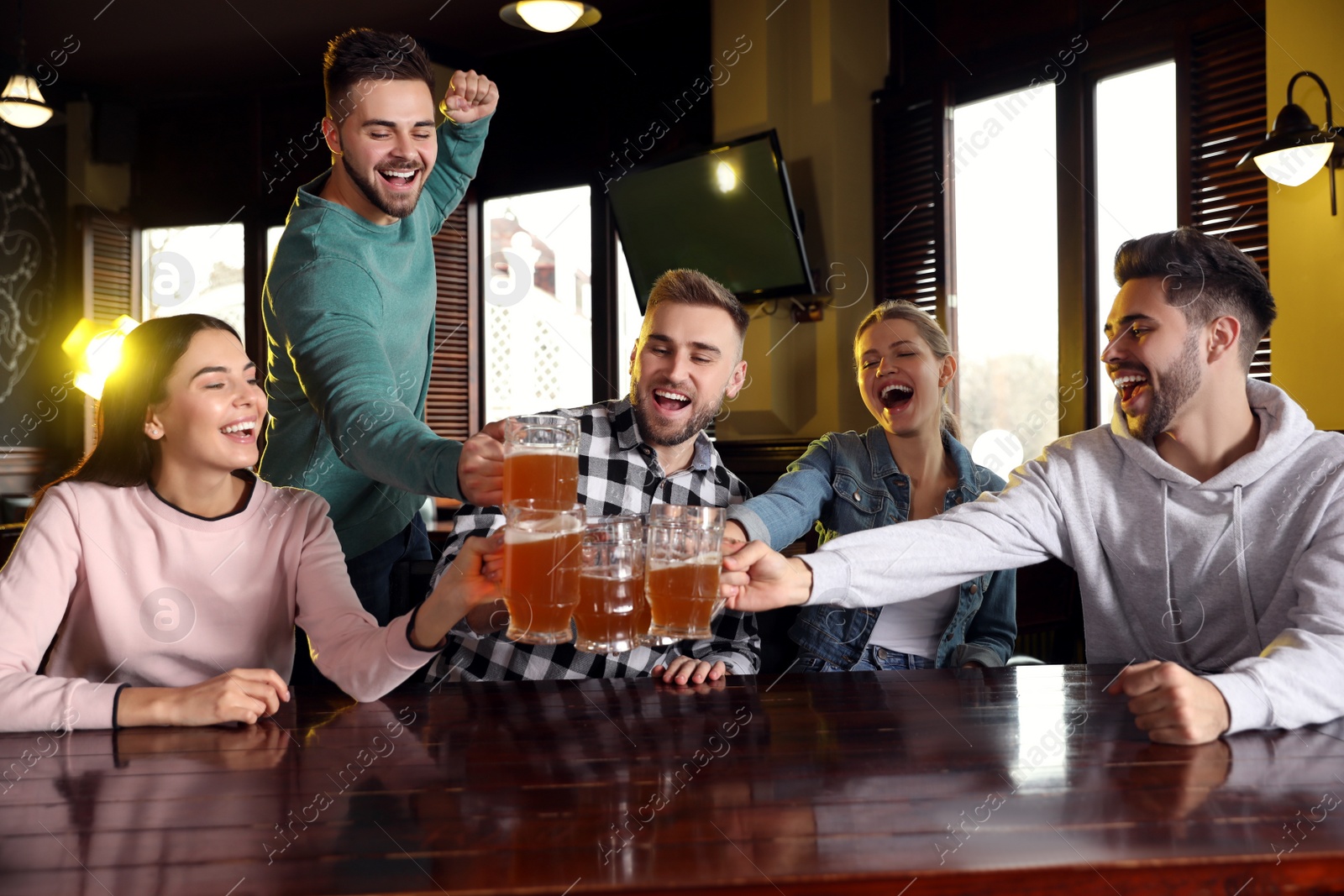 Photo of Group of friends celebrating victory of favorite football team in sport bar