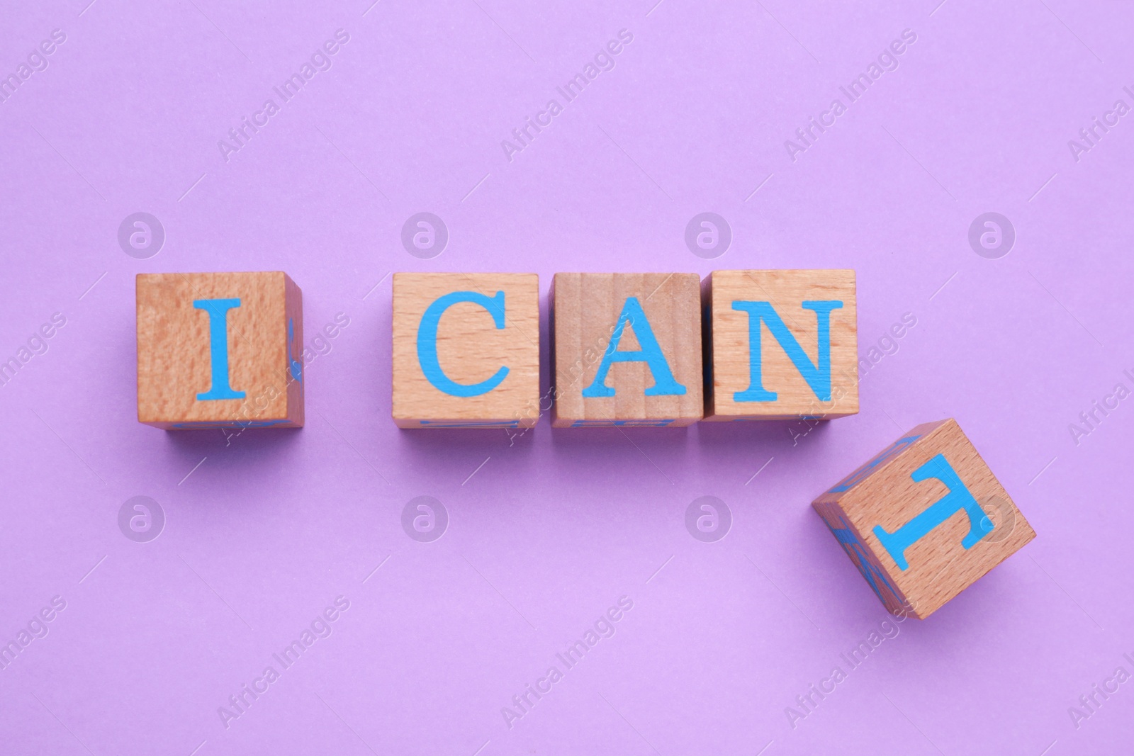 Photo of Motivation concept. Changing phrase from I Can't into I Can by removing wooden cube with letter T on violet background, flat lay