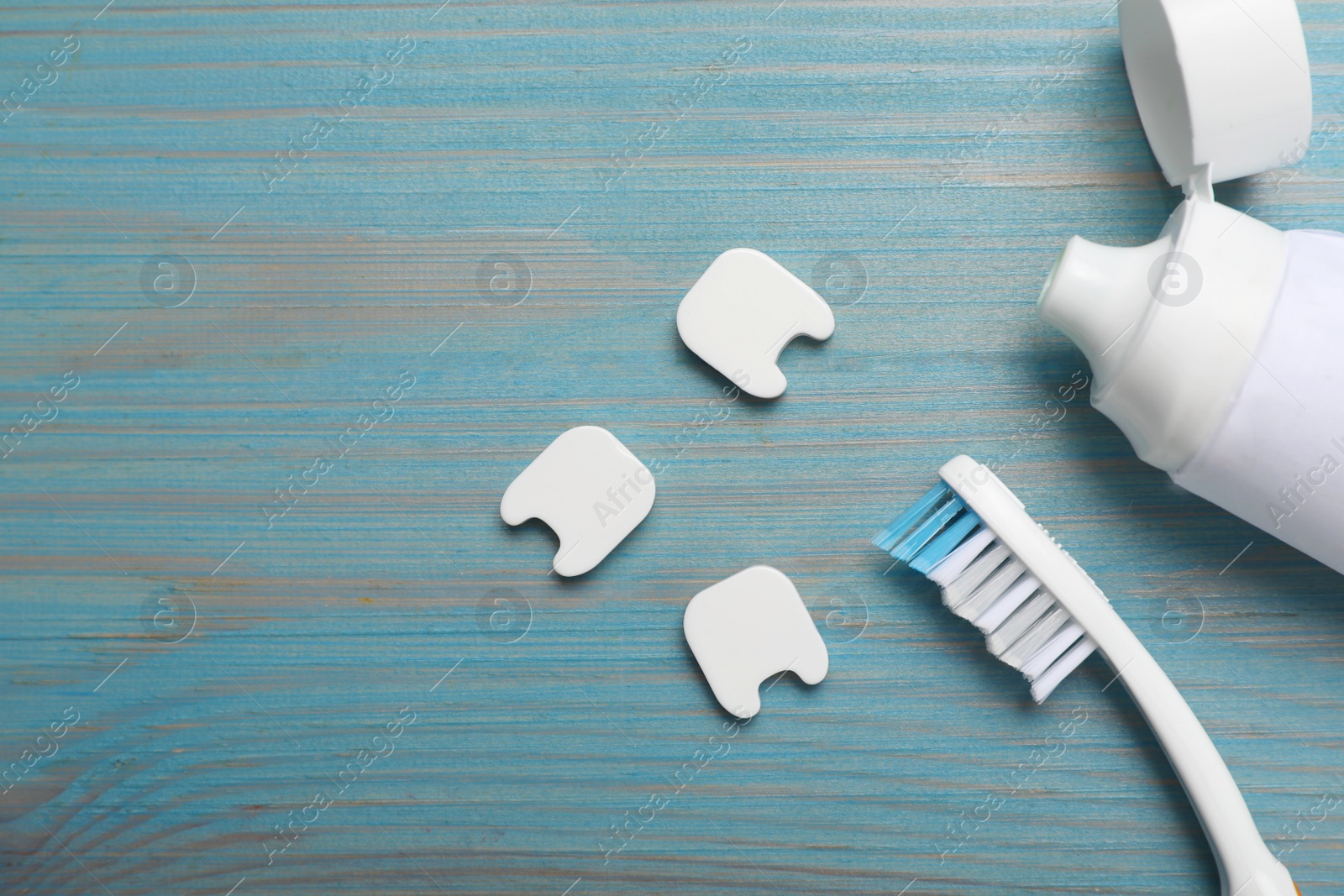 Photo of Decorative teeth, toothbrush and paste on turquoise wooden table, flat lay. Space for text