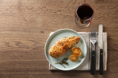 Photo of Baked lemon chicken with rosemary served on wooden table, flat lay. Space for text