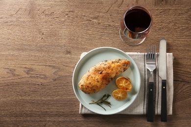 Baked lemon chicken with rosemary served on wooden table, flat lay. Space for text