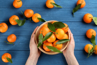 Woman with fresh ripe tangerines at blue wooden table, top view