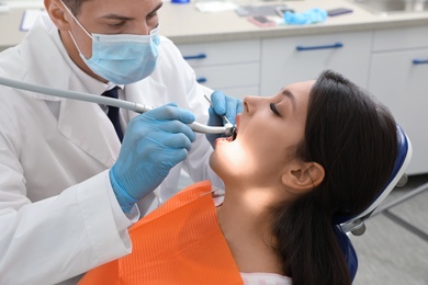 Photo of Professional dentist working with patient in clinic